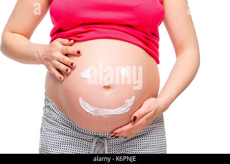 On white background belly of a pregnant woman close-up with a painted smiley Stock Photo
