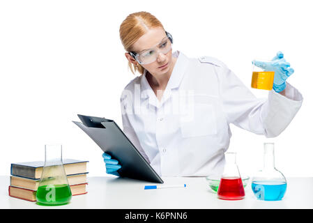 Pretty young chemist makes tests of substances in test tubes, portrait is isolated Stock Photo