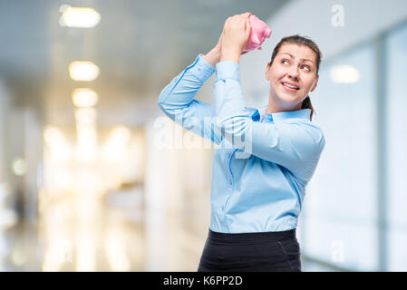 Portrait of a girl with a pink piggy bank in the studio in office Stock Photo