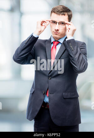 Serious businessman corrects glasses portrait in office Stock Photo