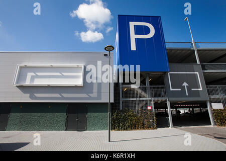 Blank billboard on a parking garage in Gouda. It’s a public building with the entrance at the right side. A huge blue parking sign with a white P Stock Photo