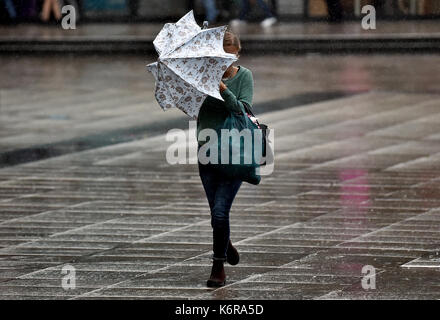 Berlin, Germany. 13th Sep, 2017. A young woman walks with her umbrella raised against the wind in Berlin, Germany, 13 September 2017. Photo: Britta Pedersen/dpa-Zentralbild/dpa/Alamy Live News Stock Photo