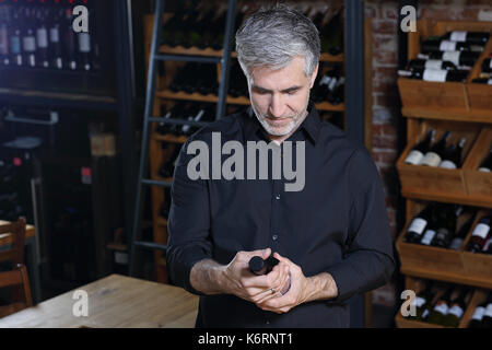 Bottles of wine in the wine cellar. Man chooses wine. Wine cellar. Wine collection. Man chooses aging wine A bottle of wine. Stock Photo