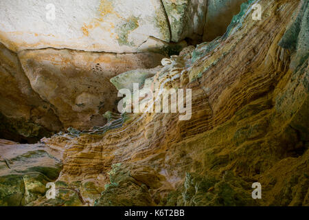 Cliff side cave, formed by sea erosion, containing evidence of sedimentation with different sediment layers having different colours. Cliffs in Malta Stock Photo