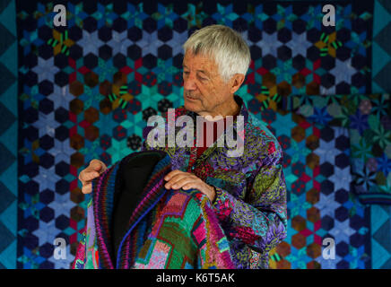 Textile artist Kaffe Fassett looks at one of his knitted coats on display during a photocall for his show 'Kaffe Fassetts Colour at Mottisfont', showcasing work from his career spanning 50 years at Mottisfont in Hampshire. Stock Photo
