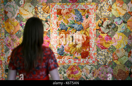 National trust staff member Sophie Wilkinson looks at a patchwork quilt by textile artist Kaffe Fassett during a photocall for his show 'Kaffe Fassett&Otilde;s Colour at Mottisfont', showcasing work from his career spanning 50 years at Mottisfont in Hampshire. Stock Photo