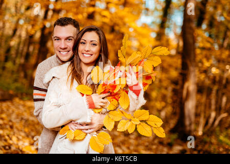 Portrait of a young smiling couple enjoying in sunny forest in autumn colors. Stock Photo