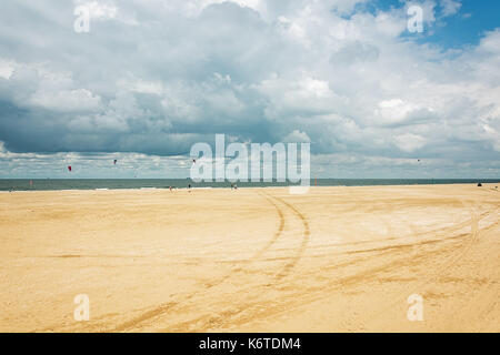 Kytesurfers on the beach of Scheveningen with in the background the seagoing ships at anchor waiting to enter the port of Rotterdam in The Netherlands Stock Photo