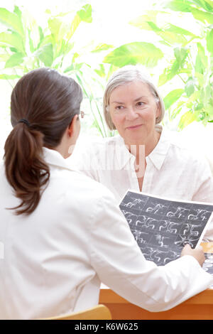 Female doctor with an mra image or angiogram discussing with a senior patient her risk to suffer an apoplectic stroke, copy space Stock Photo