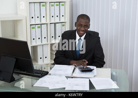 Young African Businessman Calculating Bills In Office Stock Photo