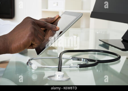 Close-up Of Male Doctor Hands Using Digital Tablet At Desk Stock Photo