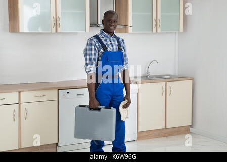 Young Happy African Technician Holding Toolbox In Kitchen Room Stock Photo