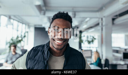 Smiling designer standing in workplace and looking at camera. Handsome young man in design office. Stock Photo