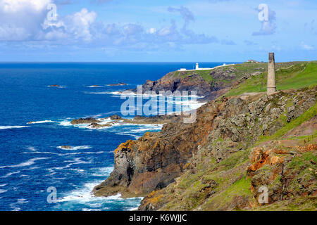 Rocky coast with old chimney from the Levant Mine and Pendeen Lighthouse, St Just in Penwith, Cornwall, England, Great Britain Stock Photo