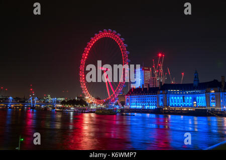 Night view of th London Eye ferris wheel located on the South bank of the Thames next to the old City Hall and close to the Houses of Parliament Stock Photo