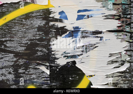 Torn paper posters glue and paint stains on messy storefront glass of closed abandoned shop. Stock Photo