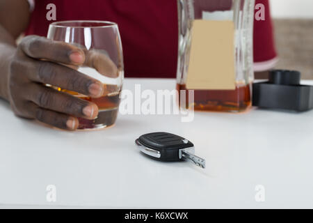 Close-up Of Man Holding Glass Of Whisky With Car Key On Table Stock Photo