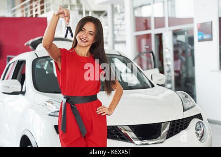 Smiling car salesman handing over your new car keys, dealership and sales concept. Happy girl the buyer. Stock Photo
