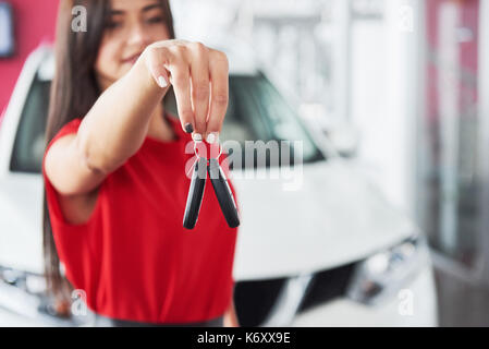 Smiling car salesman handing over your new car keys, dealership and sales concept. Happy girl the buyer. Stock Photo