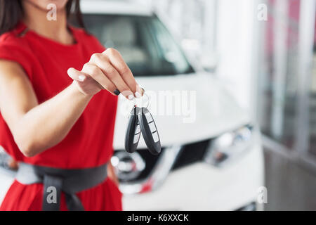 Smiling car salesman handing over your new car keys, dealership and sales concept. Happy girl the buyer. Stock Photo