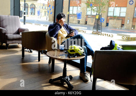 young male person sitting in cafe using computer tablet Stock Photo