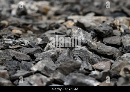 Small black rock or stones on the ground like charcoal with close up view to show texture of surface rock for background and texture. Stock Photo