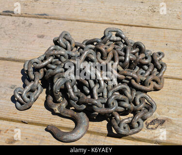 A pile of dirty rusty old chain piled on a wooden deck at a construction site. Stock Photo