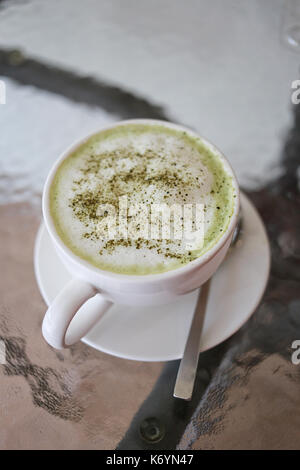 Hot green teas in white mug on food table in the restaurant cafe. Stock Photo