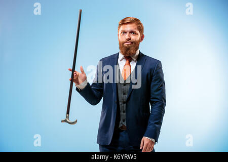 Tattooed bearded man in a suit holding cane. Stock Photo