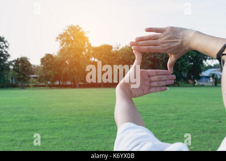 Close up of hands making frame gesture. Sunny spring sunset. Photo frame hands made by woman. Stock Photo