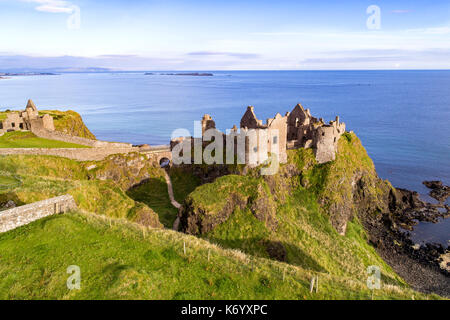 Ruins of medieval Dunluce Castle on a steep cliff. Northern coast of County Antrim, Northern Ireland, UK. Aerial view. Stock Photo