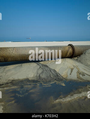 Am Strand, Langeoog.  Deutschland.  Germany.  A close-up of the industrial pipeline used as part of the active beach rebuilding, Strandaufschüttung, pumping sand up onto the sandy beaches.  A close up of a joint in pipeline that shows leakage of water, which could illustrate an environmental issue. Stock Photo
