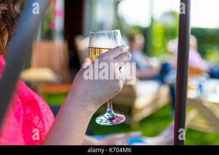 Dark haired woman drinking wine at a summer get together in the UK Stock Photo