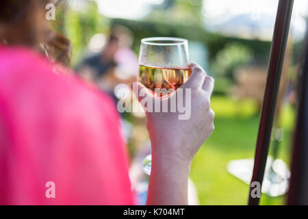 Dark haired woman drinking wine at a summer get together in the UK Stock Photo