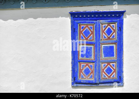 Closed vintage blue and red window on white wall of old traditional house in romania Stock Photo