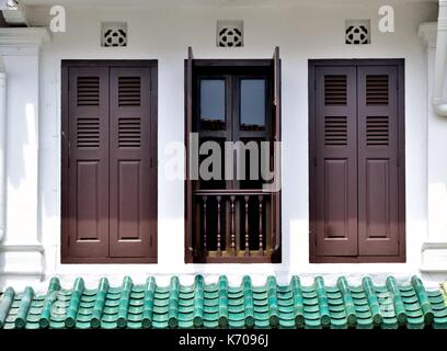 Traditional shop house exterior with white facade, brown wooden louvered shutters and Chinese tiles in Singapore's historic Everton Park Stock Photo