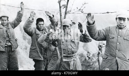 January 1953, Korea - Chinese Communist troops appproach Republic of Korea soldiers (not shown) with hands up in sign of surrender. Communists slipped under barbed wire marking United Nations side of battle lines. Stock Photo