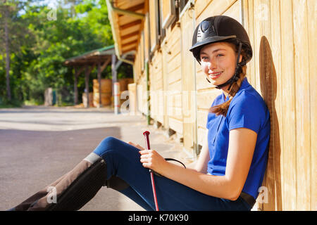 beautiful rider woman with whip is sitting on hay at sunset Stock Photo -  Alamy