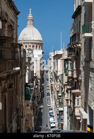 View down Zekka street (Triq Zekka) in Valletta, the capital of Malta. The dome of the Basilica of Our Lady of Mount Carmel is in the background. Stock Photo