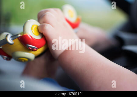 Toddler playing with colourful toy car. Harriet Baggley Stock Photo