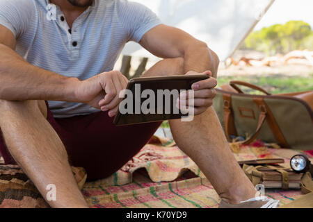 Mid section of man using tablet while sitting in tent Stock Photo