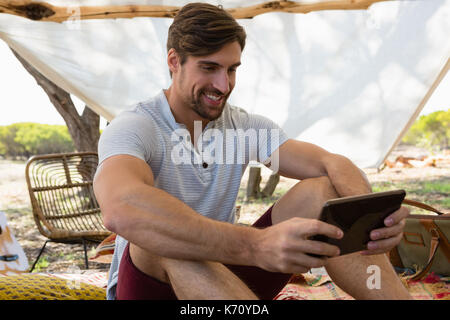 Smiling young man using digital tablet in tent Stock Photo