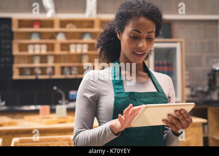 Smiling beautiful waitress using digital tablet in cafÃƒÂ© Stock Photo