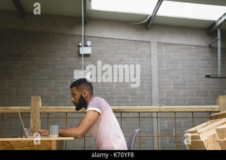 Side view of young man using laptop while sitting in cafeteria Stock Photo