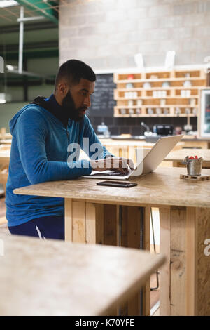 Young man using laptop while sitting at table in coffee shop Stock Photo