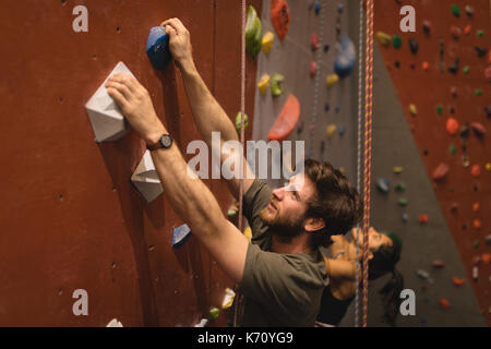 High angle view of confident male athlete climbing wall in gym Stock Photo