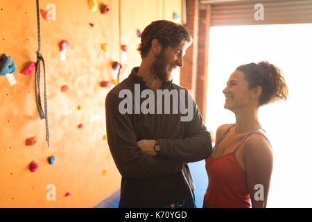 Athlete friends talking while standing by climbing wall in gym Stock Photo