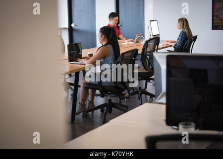 Businesswoman with colleagues using laptop at table in office Stock Photo