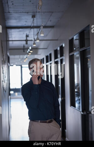 Businessman talking on mobile phone in corridor at office Stock Photo