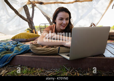 Young woman using laptop while relaxing in tent Stock Photo